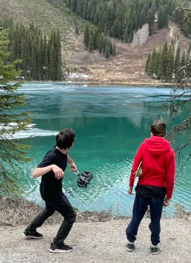 A vertical shot of two boys standing in front of the scenic Emerald Lake, British Columbia