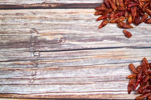 A high angle shot of piles of red chili peppers on a wooden surface