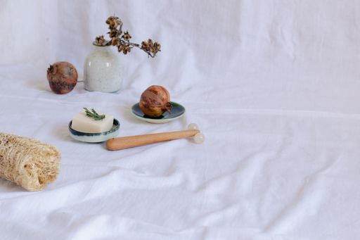 Bar of handmade vegan soap on a platter and pomegranate fruit showing the concept of sustainable and eco-friendly beauty product