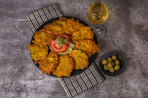 crispy shrimp omelette typical of andalucia ,spain on a round black tile on a grey background