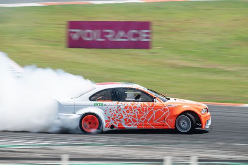 An orange white flame BMW E46 producing smoke on a trail for a drift competition