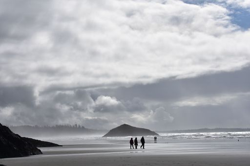 The people walking at the beach on a cloudy day in Tofino, Canada