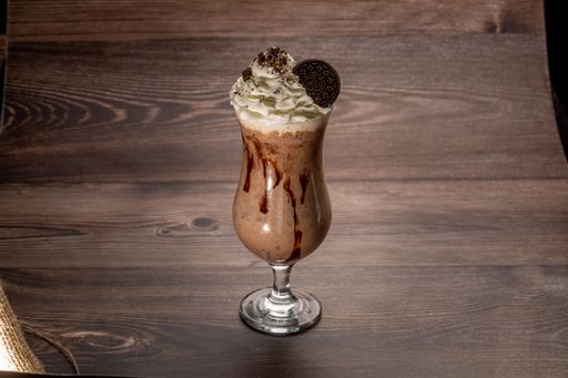 A closeup of a chocolate drink in a glass cup served on wooden background