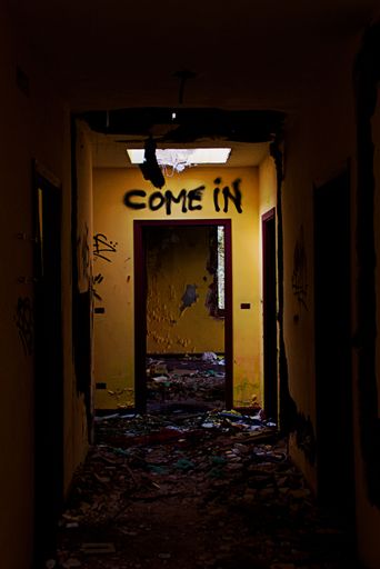 An old creepy door hallway with a "come in" text on the door