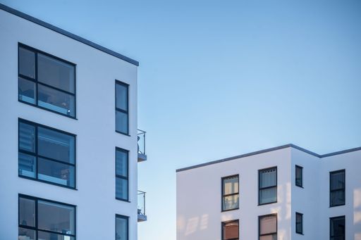 Symmetrical residential buildings with white walls and windows against a blue sky
