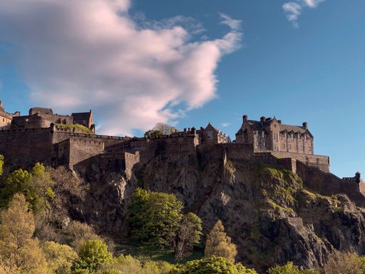 Scenic view of famous Edinburgh Castle is historic fortress against blue cloudy sky on sunny day in Edinburgh, Scotland