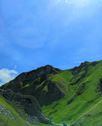 An aerial view of mountain landscape surrounded by greenery fields under blue bright sky