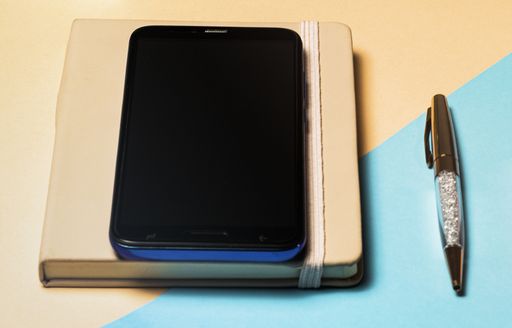 A closeup shot of a smartphone on top of a notebook with a ballpen on the side - concept for online class due to the COVID19 pandemic