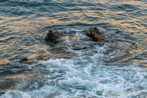 A top view of a rock formation submerged and being covered in sea waves