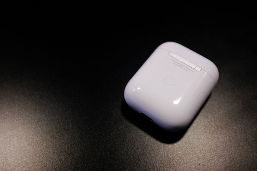 A closeup shot of a white air pod's charging case on a black background