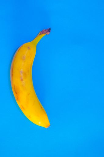 A vertical high angle shot of a fresh banana isolated on a blue surface