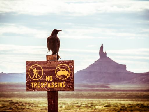 A closeup shot of  No trespassing sign and a crow in Monument Valley, Utah in USA