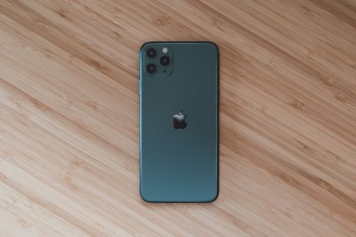 A high angle shot of a phone in a black case on a wooden surface