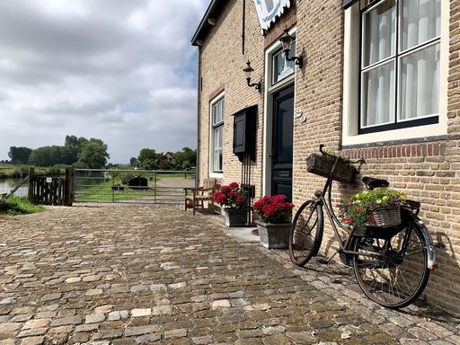 A beautiful view of a dutch barn with an old bicycle decorated with flower baskets