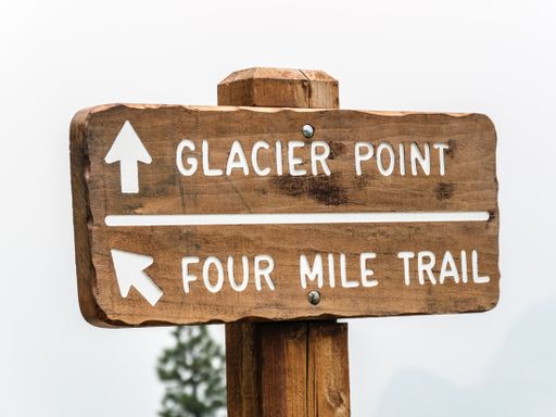 A wooden direction sign against a foggy background at the Yosemite Park, California, USA