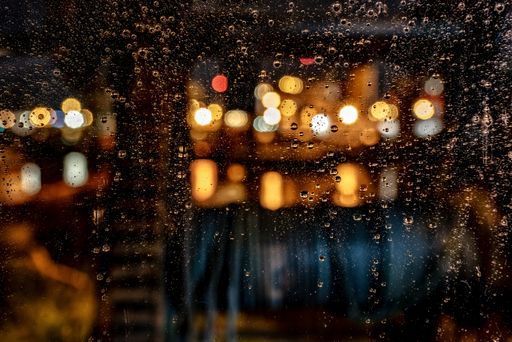 A beautiful shot of water drops on a window during a rainy night with a blurred background