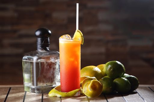 A closeup shot of Tequila Sunrise cocktail in tall glass with straw