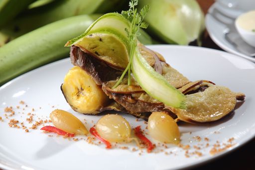A closeup shot of roasted beef fillet with plantain, pumpkin, and onion