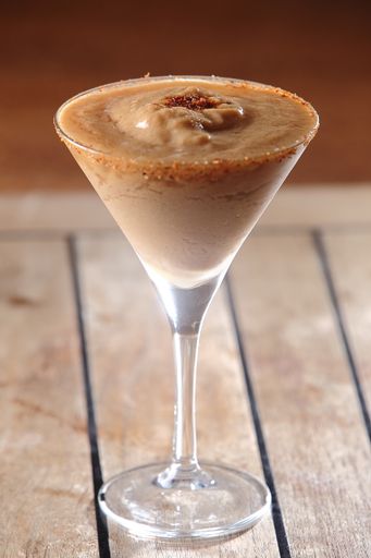 A vertical shot of a chocolate daiquiri in a martini glass on a wooden table