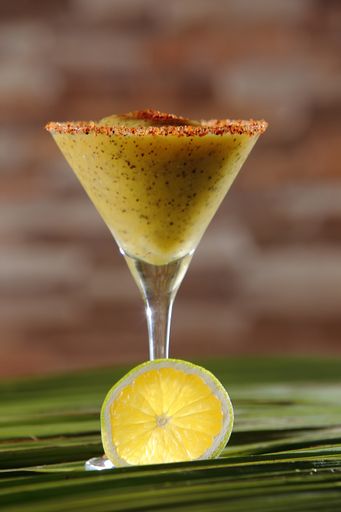 A vertical shot of maracuya daiquiri with mango, rum, vodka, lemon juice on coconut leaves surface