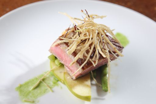 A high angle shot of medium roasted tuna loin with garnish of apples and tortilla strips