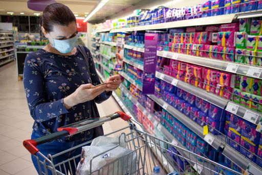 Woman wearing disposable protective face mask shopping in supermarket during coronavirus outbreak and lockdown. Prevention during covid-19 pandemic.