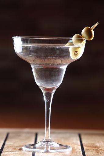 A vertical shot of a martini in a glass with a toothpick of olives