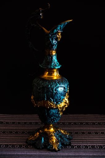 A vertical shot of a traditionally decorated pitcher on a black background