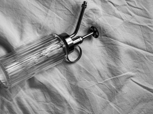 A closeup top view of a glass soap dispenser on a white cloth