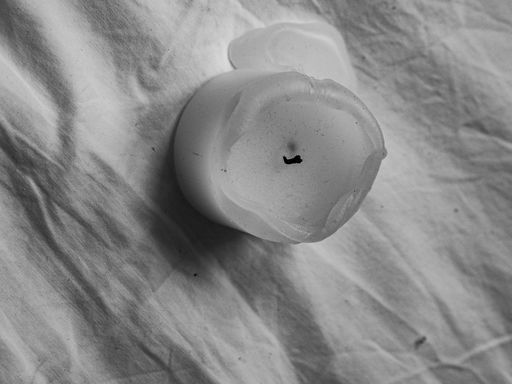 A closeup top view of a semi-burned vax candle on a white cloth