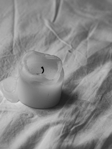 A vertical closeup shot of a semi-burned vax candle on a white cloth