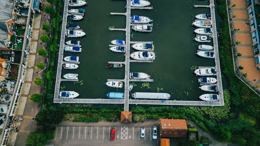 An aerial view of white boats in the water in a port in daylight in a  small town