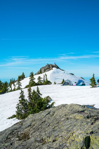A beautiful view of tents on a snowy hill under the clear sky