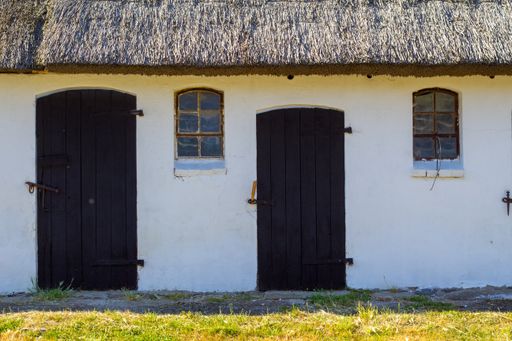 A sunny scenery of a white house with thatch roof