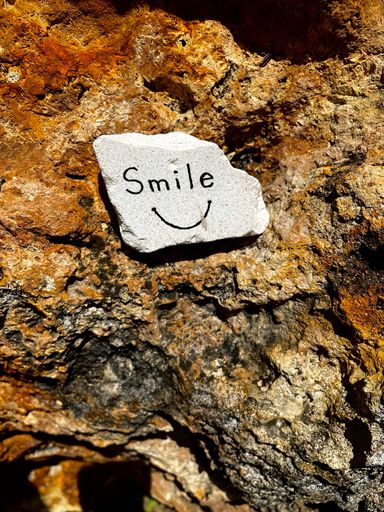 A vertical shot of a gray rock with "Smile" written on it