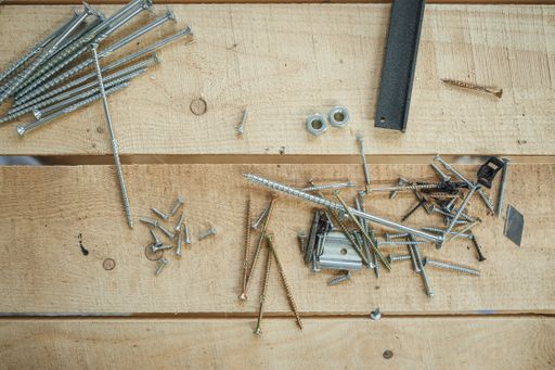 A top view of drills and screws made from steel on a wooden background in a workshop