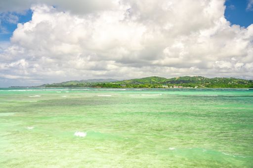 A beautiful tropical bay with clear green water under a cloudy sky
