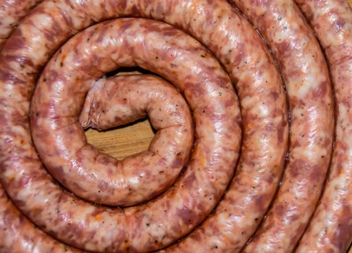 An overhead shot of coiled raw sausage on a wooden board