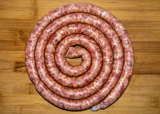 An overhead shot of coiled raw sausage on a wooden board