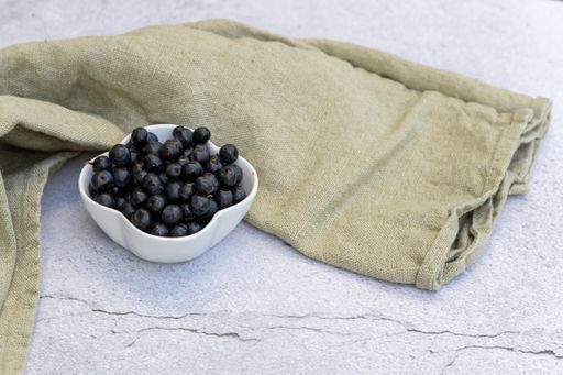 A closeup of blueberries in a bowl on the table with fabric on it under the lights