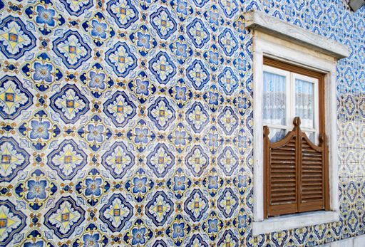 A shot of orange and blue mosaic tiles forming a wall with a window in the middle