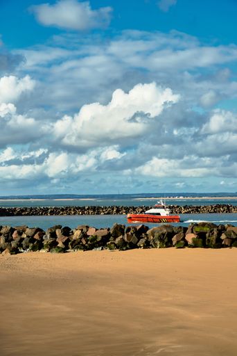 A vertical shot of a yacht near the sandy shore on a sunny day