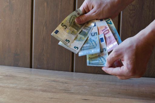 A view of human hands holding banknotes in Euro in brown background