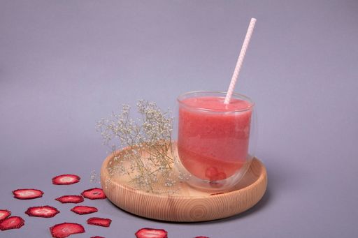 A glass of grapefruit smoothie with dried strawberries next to it