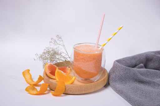 A closeup of a glass of fruit smoothie isolated on white background.