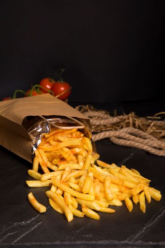 A closeup vertical shot of fresh french fries coming out of the bag