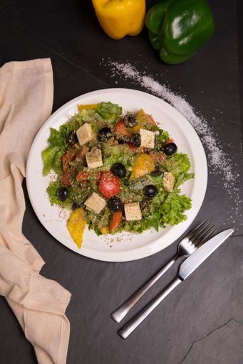 A top view of salad with olives, cheese, lettuce and colorful peppers