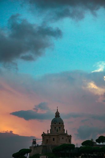 A vertical shot of a cathedral at a distance on colorful cloudy sunset sky background