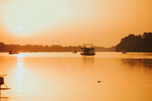 The Sava river between Bosnia and Croatia with boats floating on it under a bright golden sunset sky