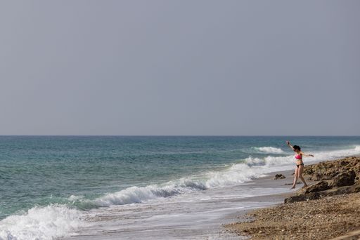 A middle aged woman walking on the beach of the Mediterranean Sea
